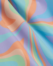 A close-up of Psycho Bunny MENS BLOOMINGTON SWIM TRUNK - B6W941A2PO with a colorful, psychedelic pattern. The design features wavy, swirling shapes in shades of orange, light blue, turquoise, and green on a blue background, creating a dynamic and vibrant visual effect. The fabric appears smooth and glossy.