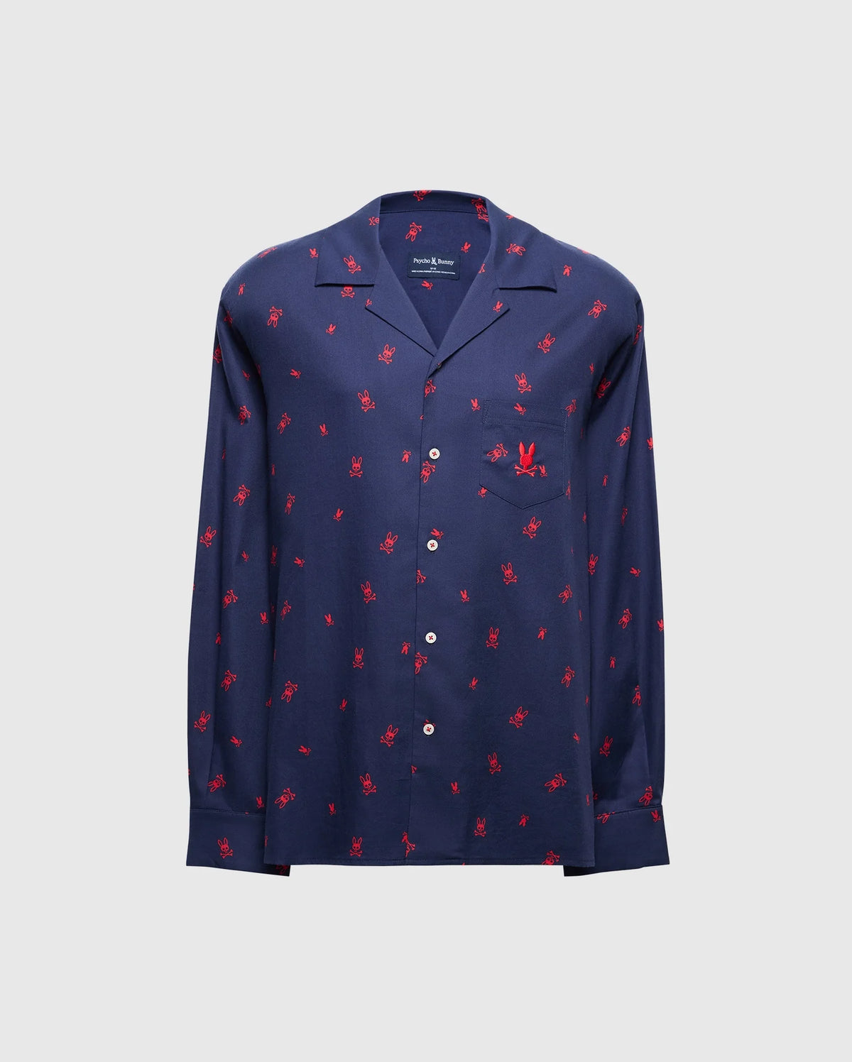 The MENS ALL OVER PRINT FLANNEL PAJAMA SET - B6X343E200 from Psycho Bunny is a stylish navy blue button-up shirt adorned with a vibrant red palm tree print on a light gray background. Designed for maximum comfort, it resembles a soft flannel sleep set and features long sleeves and a chest pocket.
