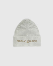 The MENS BEANIE AND SCARF BOX SET - B6X353E200 by Psycho Bunny includes a light gray ribbed beanie with "Psycho Bunny" and a bunny logo embroidered in gold on the folded brim. Crafted from premium 100% cotton, it provides both warmth and style.