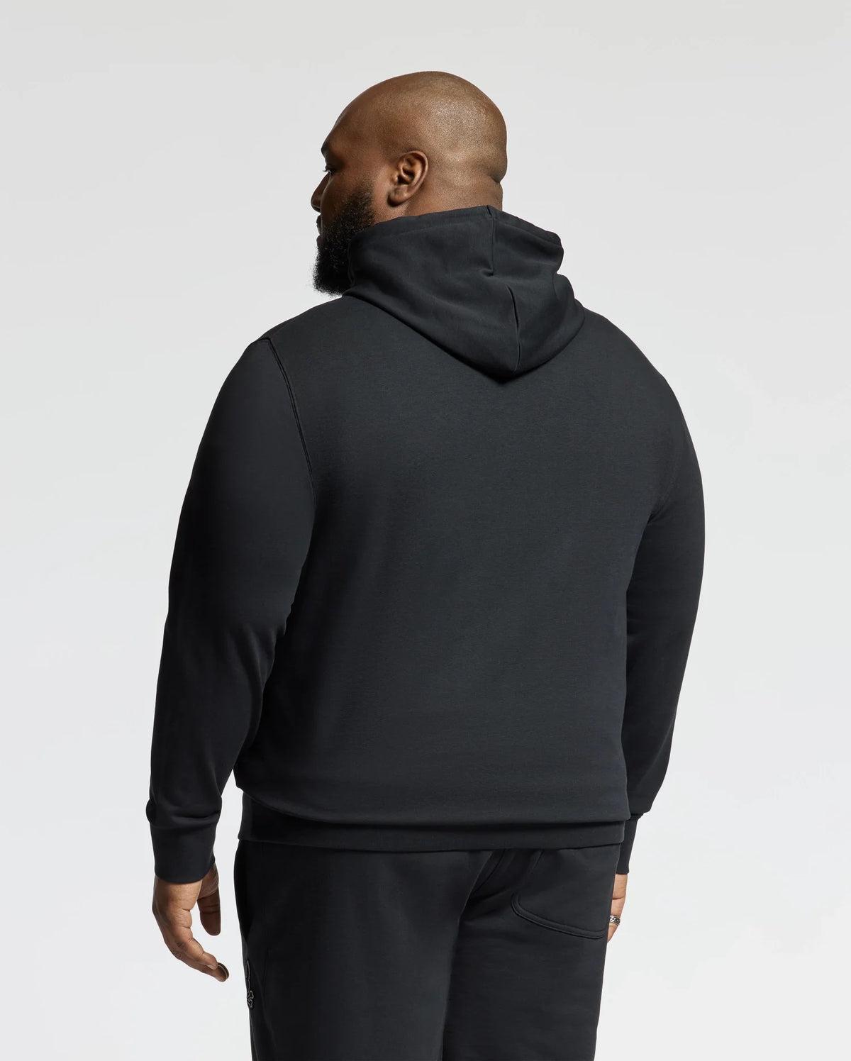 A man wearing a Psycho Bunny BIG AND TALL ALEXANDER HOODIE - B9H154E200 in black, along with matching pants, is shown from the back against a plain background.