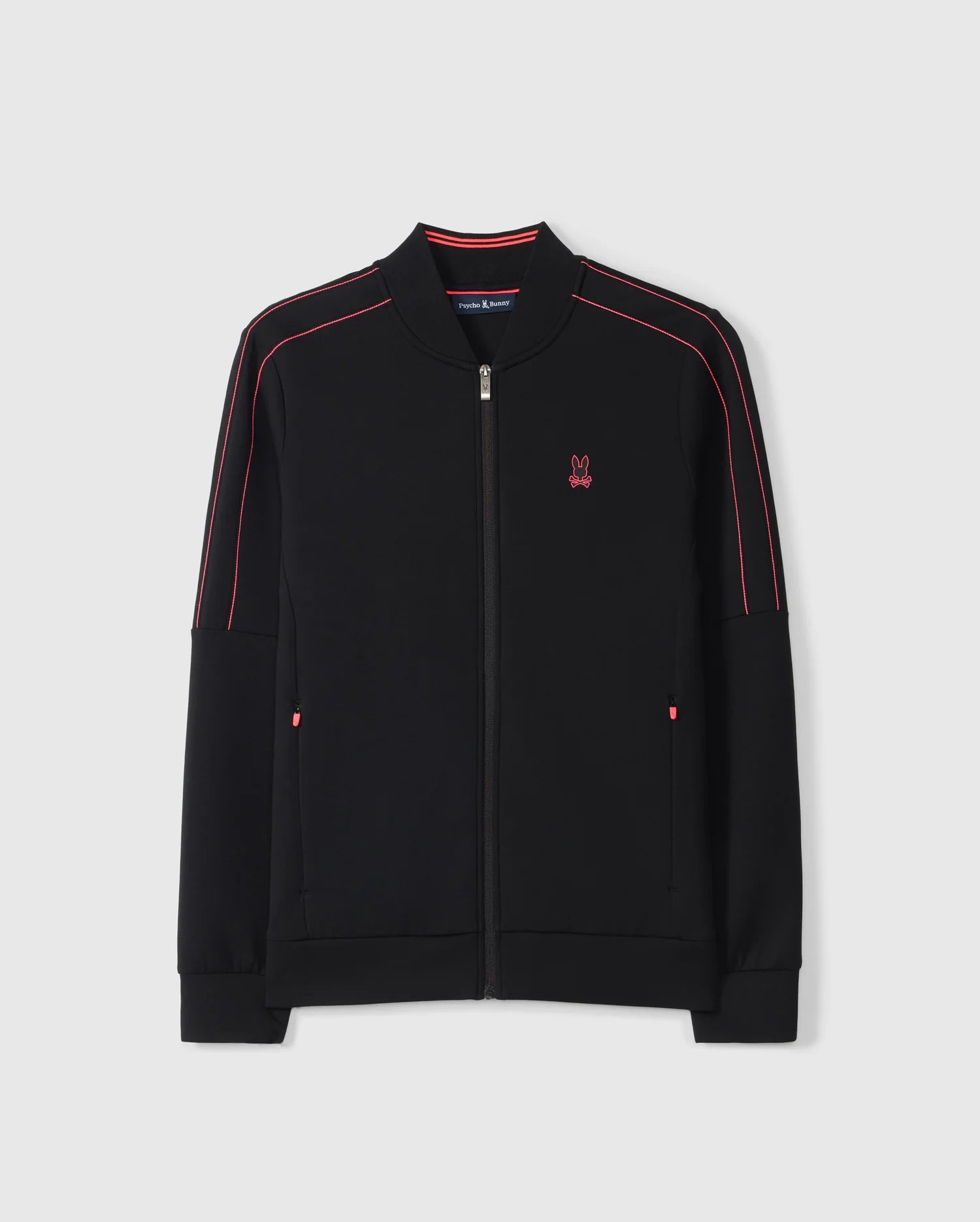 The Psycho Bunny BIG AND TALL TRAVIS TRACK JACKET - B9J142D200 is a black cotton-blend track jacket with a front zipper and red piping on the shoulders and sleeves. It features a small red embroidered logo on the chest against a plain light grey background.