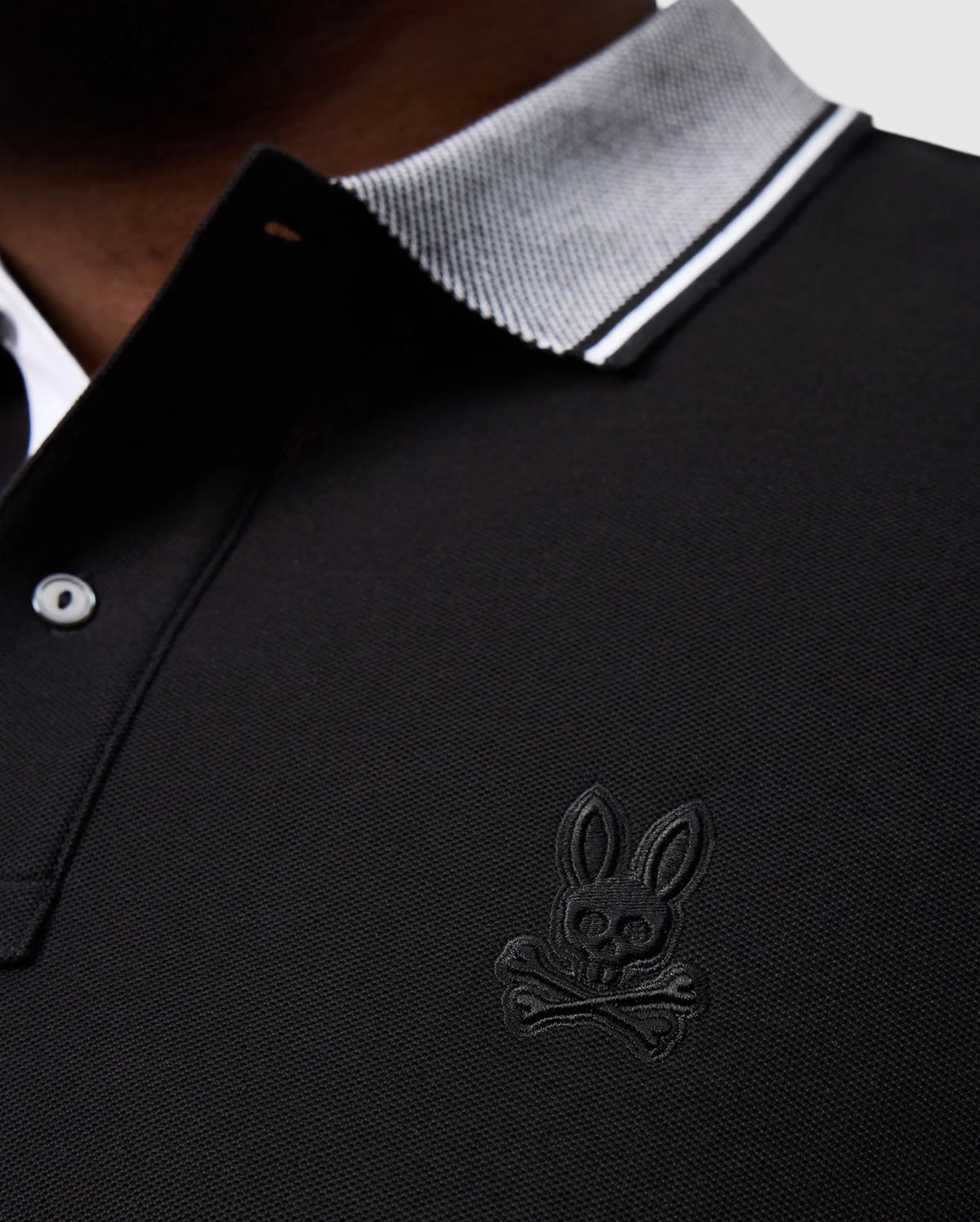 The Psycho Bunny BIG AND TALL MALTON PIQUE POLO SHIRT - B9K950D200 features luxurious Pima cotton in black with a white and gray collar, highlighted by the iconic embroidered rabbit skull and crossbones on the left chest.