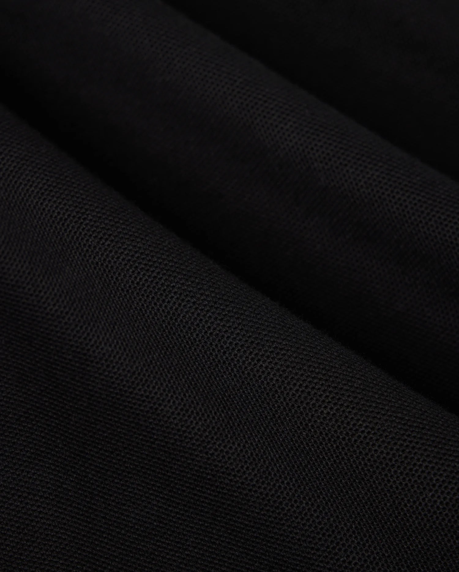 A close-up of black Pima cotton fabric drapes gracefully, showcasing soft, diagonal folds and shadows on this Psycho Bunny BIG AND TALL MALTON PIQUE POLO SHIRT - B9K950D200.