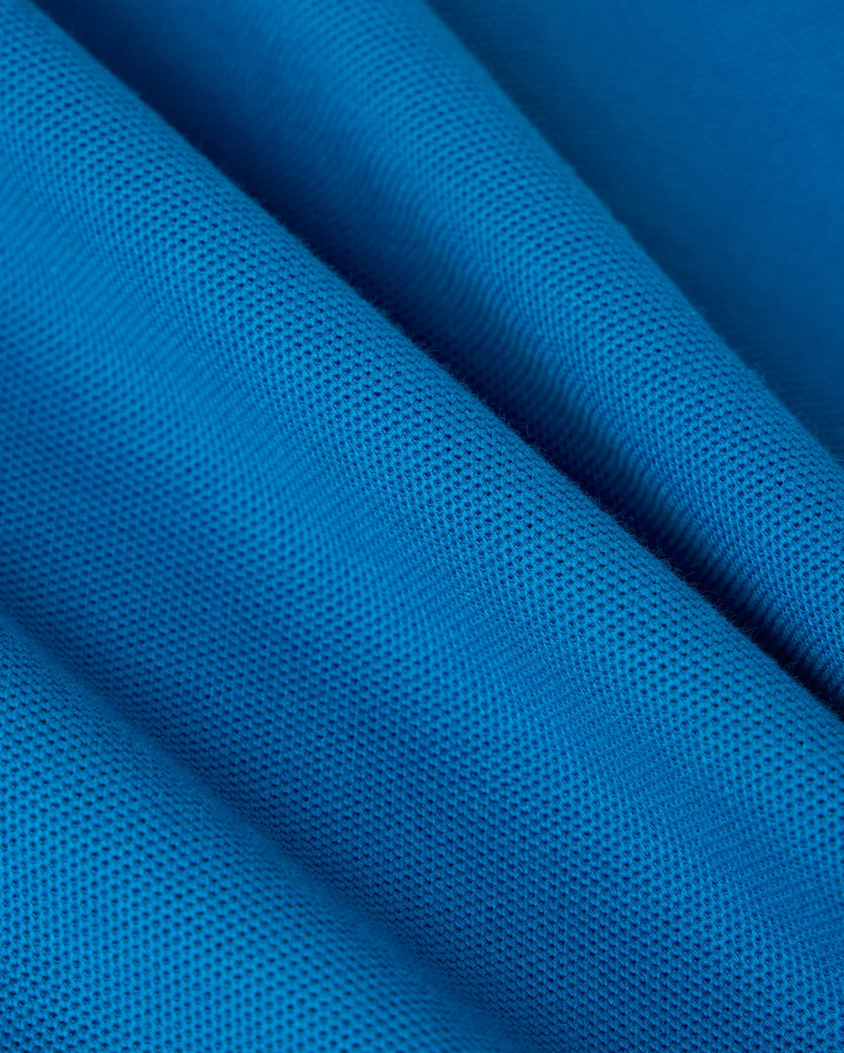 The BIG AND TALL MALTON PIQUE POLO SHIRT by Psycho Bunny showcases blue textured fabric with a fine diamond pique pattern. The pima cotton creates gentle waves and shadows, while the surface has a slightly matte finish, reminiscent of its luxe design.