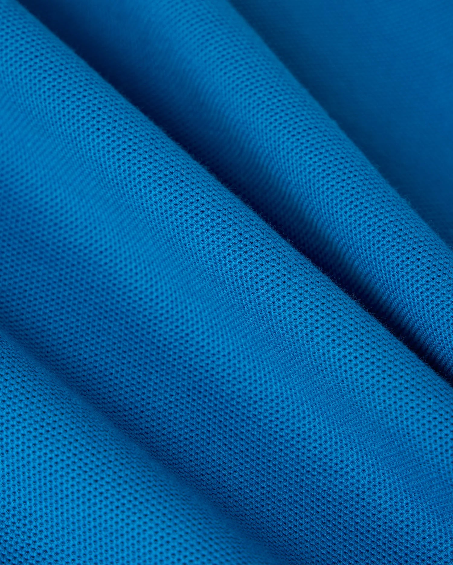The BIG AND TALL MALTON PIQUE POLO SHIRT by Psycho Bunny showcases blue textured fabric with a fine diamond pique pattern. The pima cotton creates gentle waves and shadows, while the surface has a slightly matte finish, reminiscent of its luxe design.