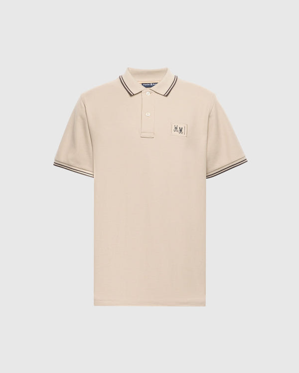 The Psycho Bunny Men's Big and Tall Monroe Pique Polo - B9K964D200 is a regular-fit, beige polo made from Pima cotton, featuring a buttoned collar with black stripes on the edges, short sleeves with striped cuffs, and an embroidered chest emblem.