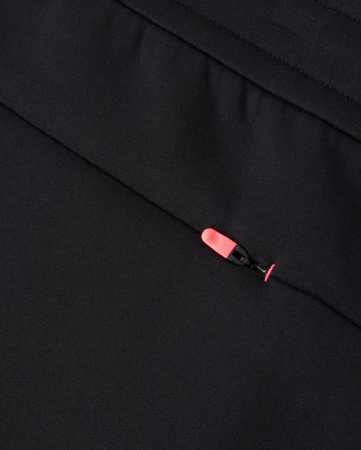 Close-up of the black BIG AND TALL TRAVIS TRACK PANT (B9P143D200) by Psycho Bunny, featuring a hidden pocket with a stylish black and pink zipper pull. The pocket blends seamlessly, enhancing both style and functionality in the stretchy fabric.