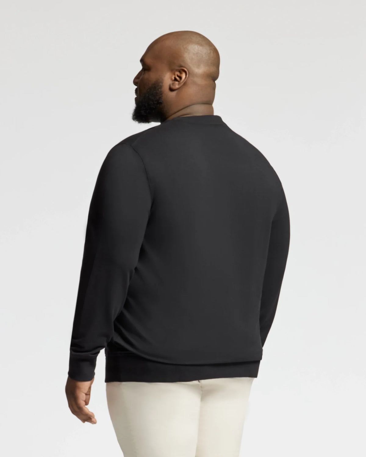 A bearded individual, facing away, models the Psycho Bunny BIG AND TALL LAVATA FRENCH TERRY SWEATSHIRT (B9S159E200) in black. Ideal for big and tall sizes, it pairs with light pants against a plain white backdrop.