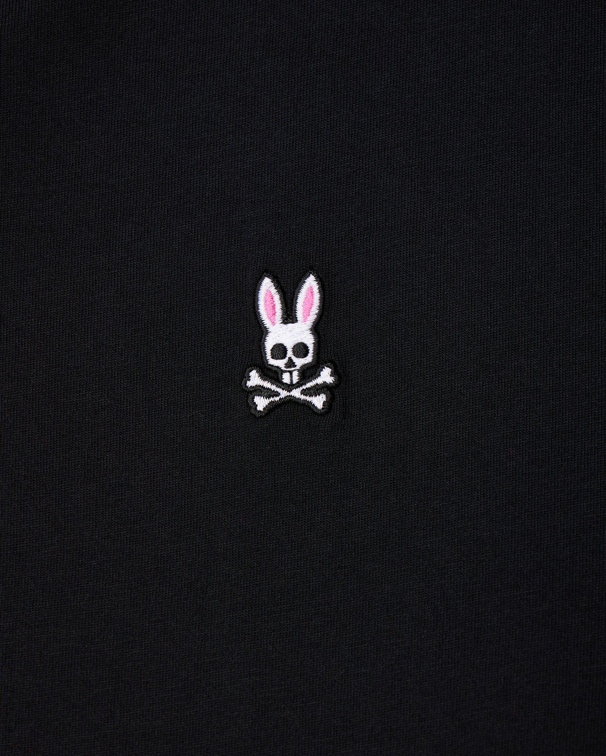 The Psycho Bunny Men's Big and Tall Classic Crew Neck Tee (B9U014CRPC) showcases a white skull with rabbit ears, pink interior, and crossbones. Made from 100% Pima cotton, this elegant design pops on its black fabric background.
