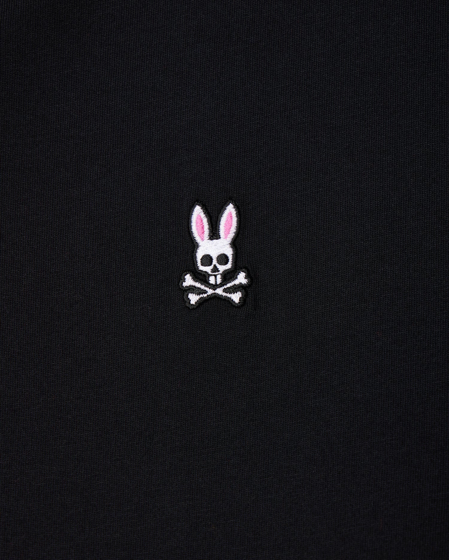The Psycho Bunny Men's Big and Tall Classic Crew Neck Tee (B9U014CRPC) showcases a white skull with rabbit ears, pink interior, and crossbones. Made from 100% Pima cotton, this elegant design pops on its black fabric background.