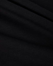 A close-up of black, finely ribbed fabric with subtle folds from the Psycho Bunny MENS BIG AND TALL CLASSIC CREW NECK TEE (B9U014CRPC) reveals a textured appearance. Lighting highlights its ridges and grooves, indicating it is soft and flexible 100% Pima cotton.