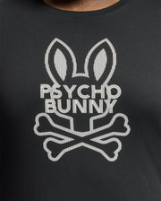 The BIG AND TALL DUMON GRAPHIC TEE - B9U271E200 by Psycho Bunny is a black Pima cotton tee featuring a stylized bunny with long ears and crossbones, along with the text "PSYCHO BUNNY," offering a mix of playful and edgy aesthetics.