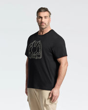 A man with short hair and a beard wears the Psycho Bunny MENS BIG AND TALL MELBOURNE GRAPHIC TEE made from eco-friendly Peruvian Pima cotton. The black tee features a large bunny graphic and text. He pairs it with light pants, standing against a white backdrop, slightly facing right.
