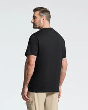 A man in a black Psycho Bunny Men's Big and Tall Melbourne Graphic Tee (B9U410F200) and beige cargo shorts poses relaxedly, showcasing his left side against a plain white background. The tee is made from eco-friendly Peruvian Pima cotton for optimal comfort and durability.