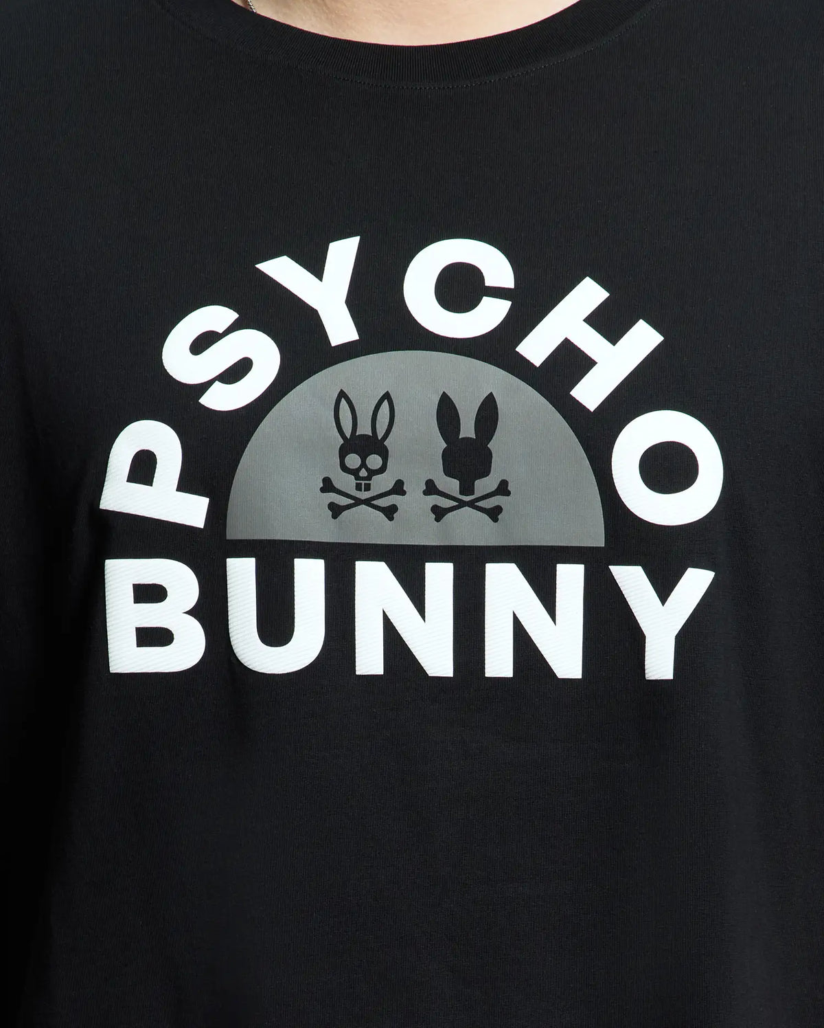 The Men's Big and Tall Goldie Graphic Tee from Psycho Bunny features "Psycho Bunny" in white on premium Pima cotton. Below it, a semicircle displays two bunny skull logos with crossbones, one light and one dark, highlighting the edgy graphic style.