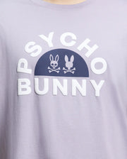Close-up of the Men's Big and Tall Goldie Graphic Tee (B9U606F200) by Psycho Bunny in light purple, crafted from soft Pima cotton. It showcases bold white "Psycho Bunny" text with a dark arch and bunny graphic icons, one resembling a skull and crossbones.
