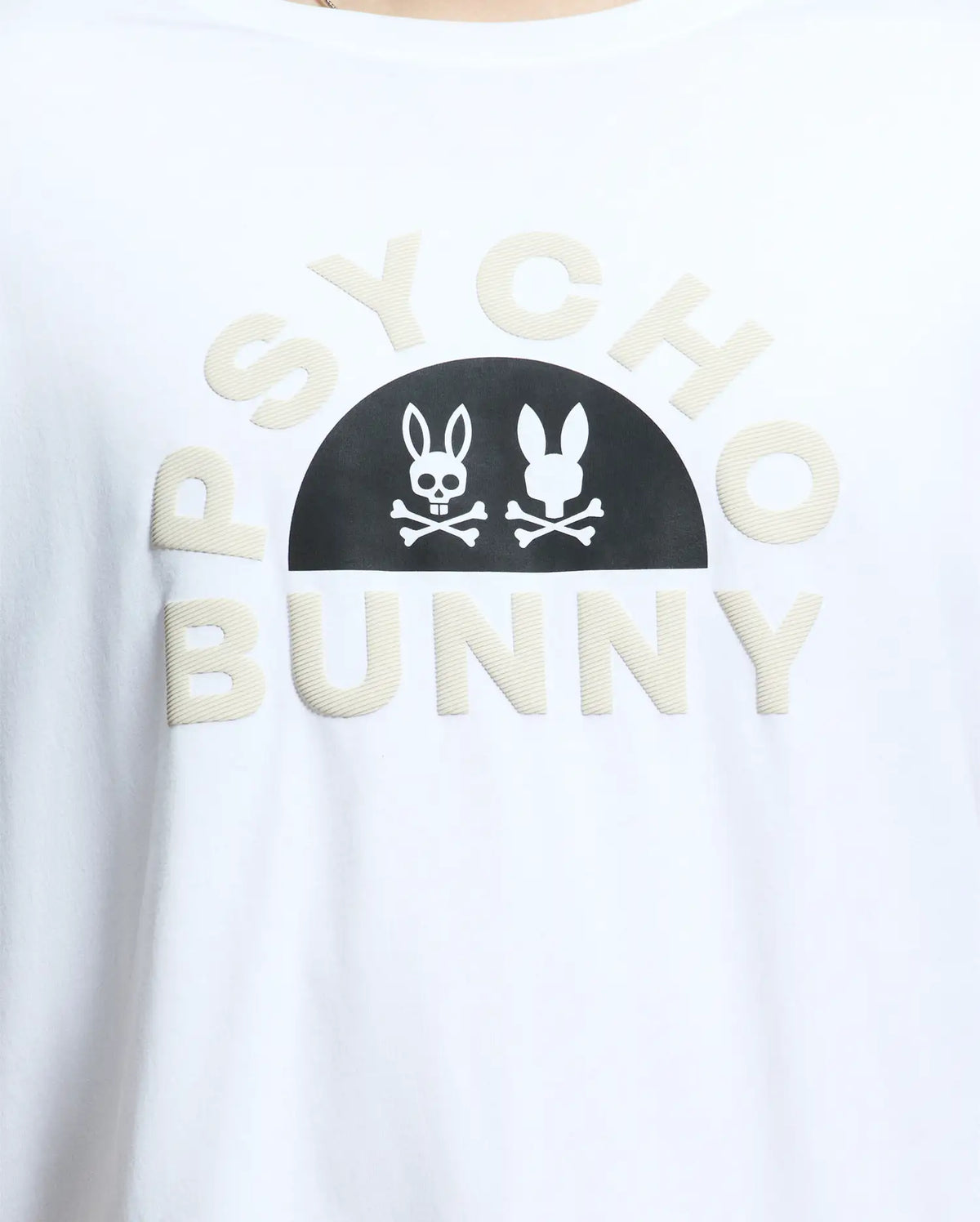 Close-up of a MENS BIG AND TALL GOLDIE GRAPHIC TEE - B9U606F200 by Psycho Bunny, crafted from Peruvian Pima cotton. It features "Psycho Bunny" in beige letters with a black half-circle displaying a white skull-and-crossbones within the bunny graphic.