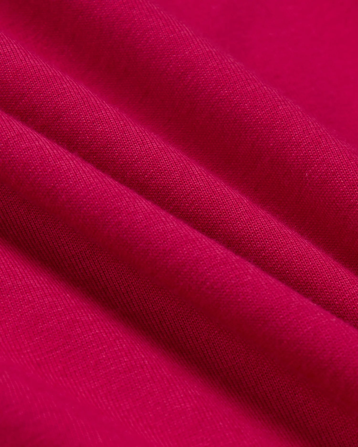 The Psycho Bunny BIG AND TALL TACOMA GRAPHIC TEE - B9U909D200 features bright pink fabric with soft, wavy folds and a textured weave pattern. It resembles fine Pima cotton, offering a smooth, vibrant appearance that catches light subtly.
