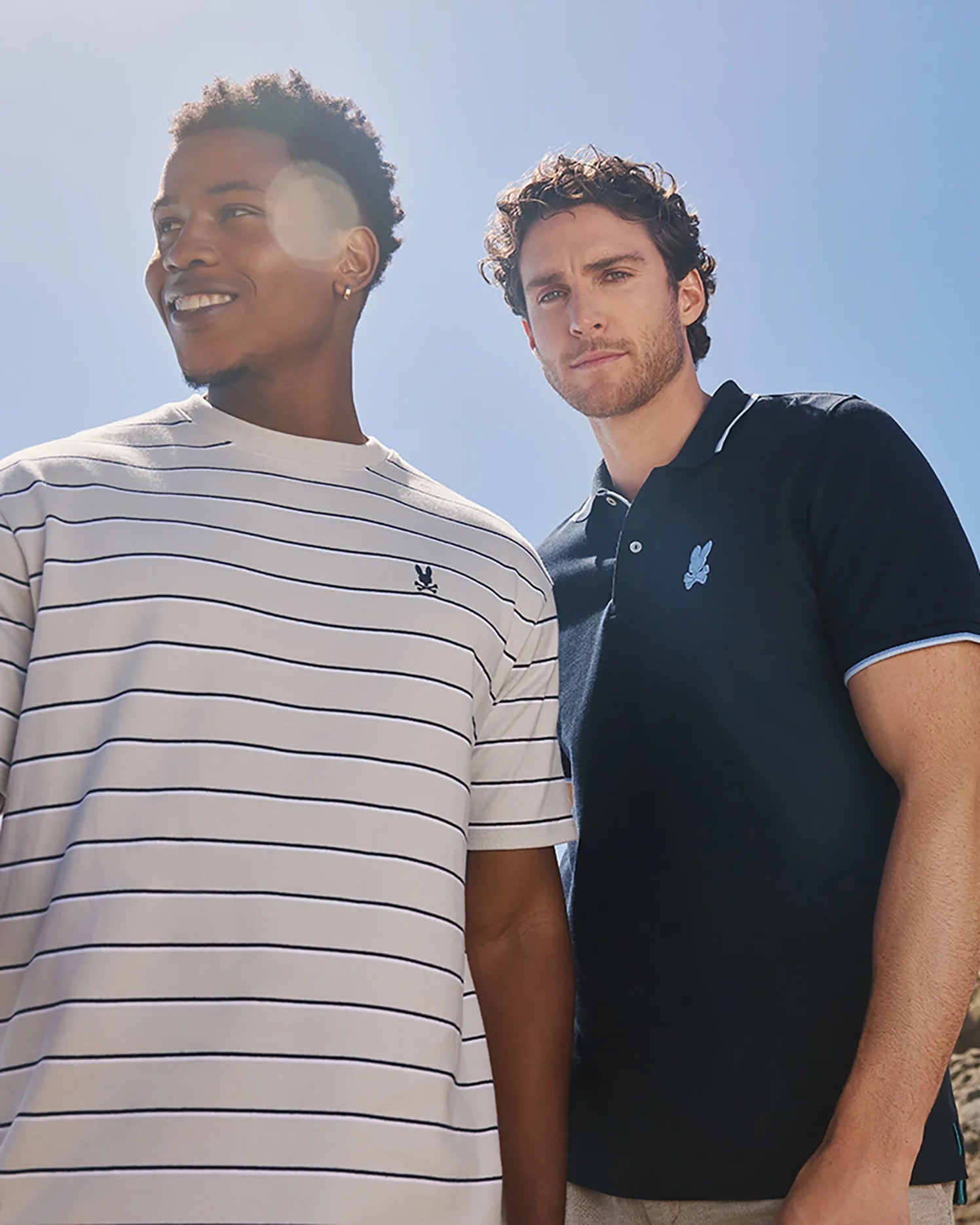 A model wearing the mens pima cotton alton stripe heavy weight tee standing next to another model wearing the Men's Houston pique polo shirt in navy outside in the sunshine