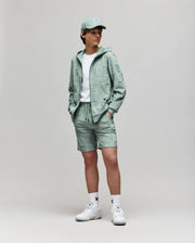 A person stands against a plain background wearing the Psycho Bunny KIDS KELVIN FULL ZIP TOWEL TERRY HOODIE (KT0500004) in mint green with matching shorts, a white t-shirt, white socks, and white sneakers. Hands are in the hoodie pockets.