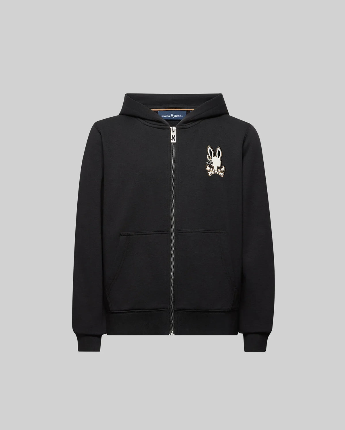 The KIDS WADE CORD PATCH ZIP HOODIE (KT0500016) by Psycho Bunny is a black zip-hoodie with front pockets, crafted from premium cotton, and features an embroidered Bunny head with crossbones on the left chest.