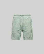 The Psycho Bunny MENS KELVIN TOWEL TERRY SWEATSHORT (MB0900006) features light green cotton-blend fabric with a jacquard terry checkered texture and embossed designs on each square, shown against a plain gray background.