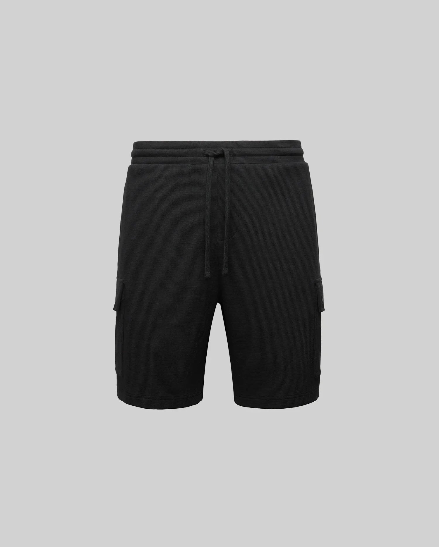 The Psycho Bunny MENS RON WAFFLE CARGO SHORT (MB0900012) is shown in black with an elastic waistband, drawstring, and side cargo pockets, displayed on a plain gray background.