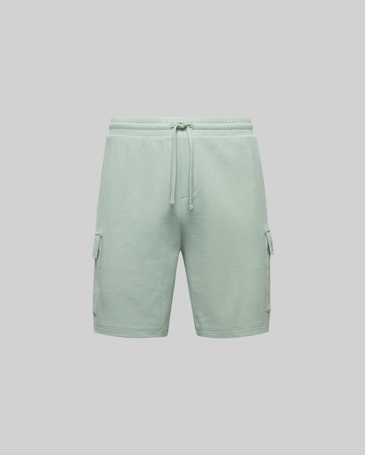 Psycho Bunny MENS RON WAFFLE CARGO SHORT (MB0900012) in light green features an elastic waistband, drawstring, large side flap pockets, and subtle embroidered logos, shown against a plain gray background.