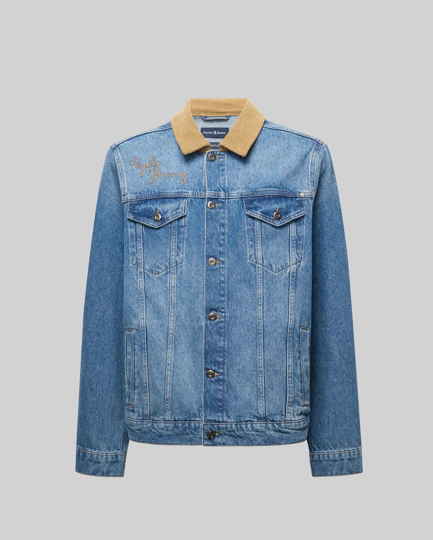 The Psycho Bunny MENS WADE DENIM TRUCKER JACKET - MO1100015 features blue denim, a tan corduroy collar, button closure, chest and side pockets, plus a bunny patch on the left shoulder, shown against a plain gray background.