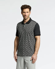 A man is wearing a Psycho Bunny MENS BECKETT PIQUE POLO - MT0100022 with black sleeves and collar, paired with light gray pants, against a light background.