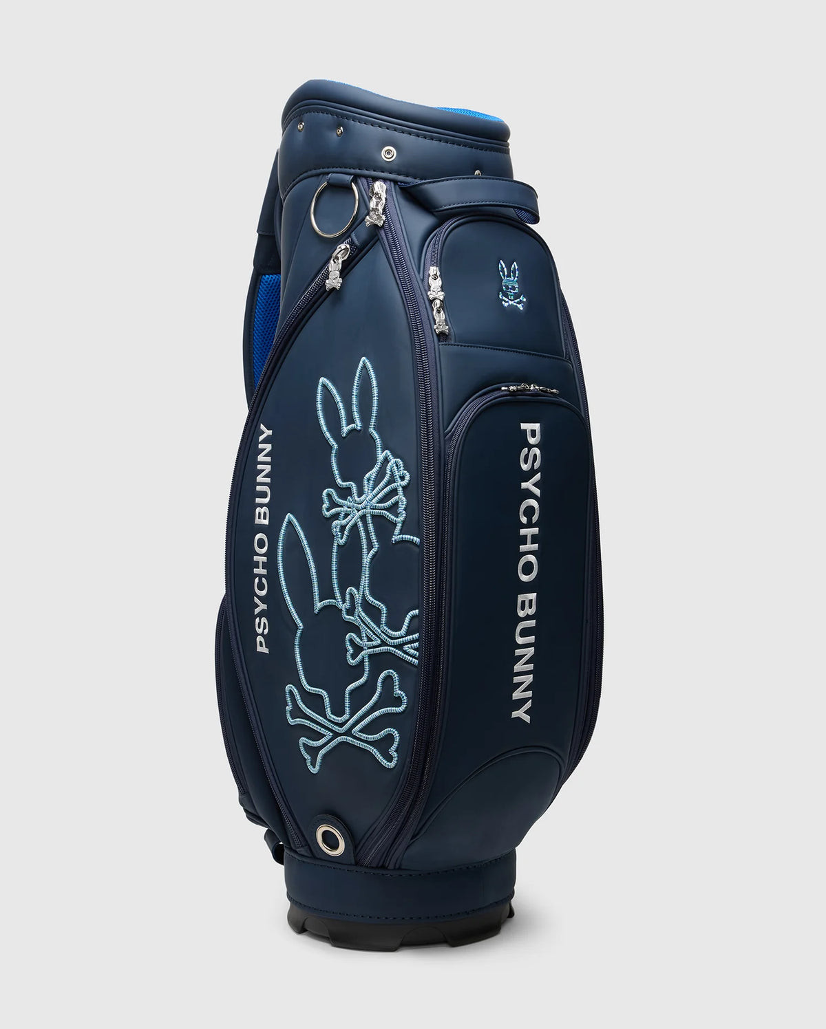 The OUTLINE BUNNY GOLF TOUR BAG - PBMG4FC1 by Psycho Bunny is navy blue with "Psycho Bunny" in white. It features a large light blue stylized rabbit logo, is crafted from durable polyurethane, and includes multiple zippered compartments with a detachable strap for easy transport.