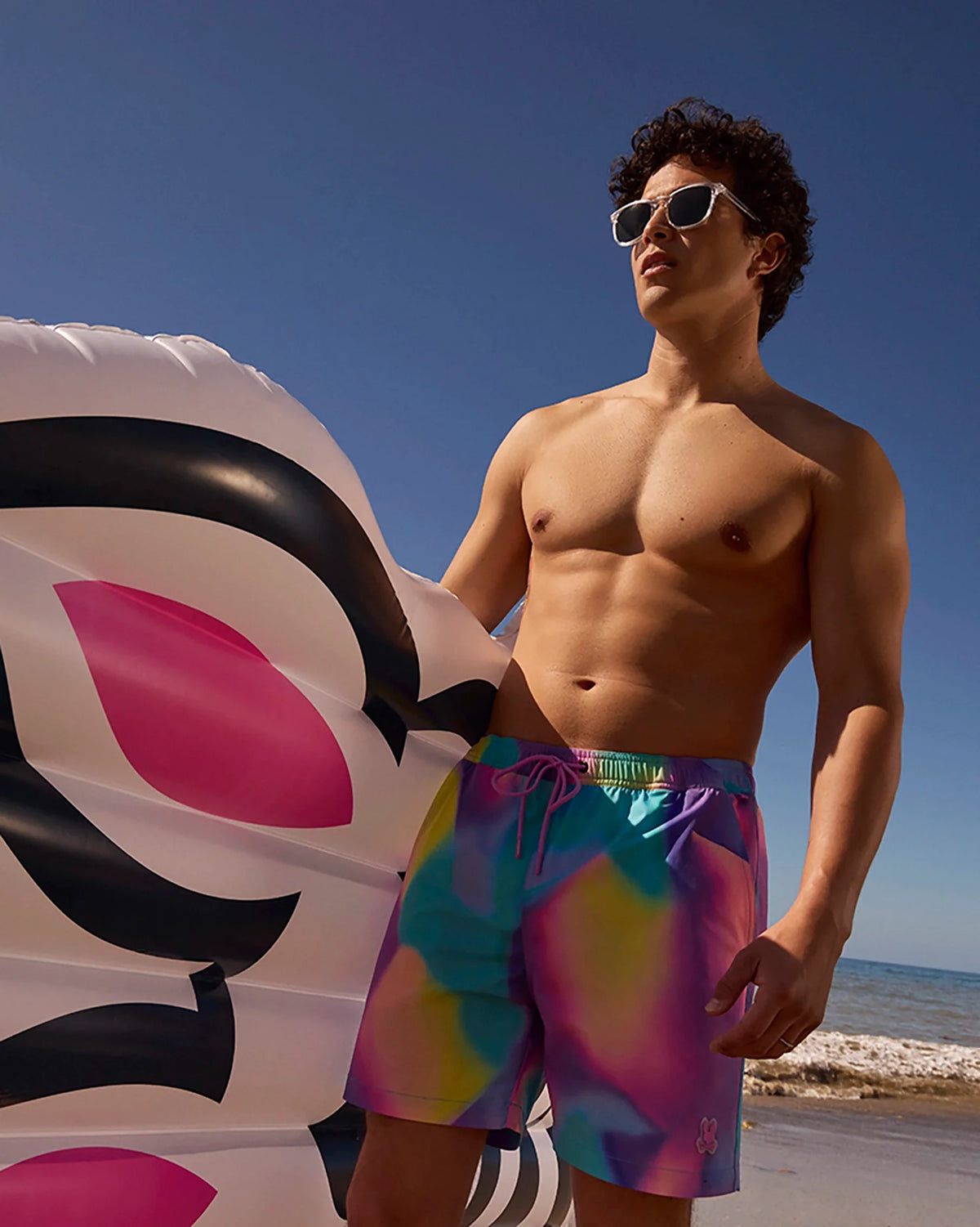 Male model wearing men's tyler print swim trunk at the beach