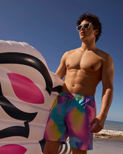 Male model wearing men's tyler print swim trunk at the beach