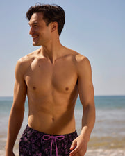 Male model wearing rendon print swim trunk in black on beach
