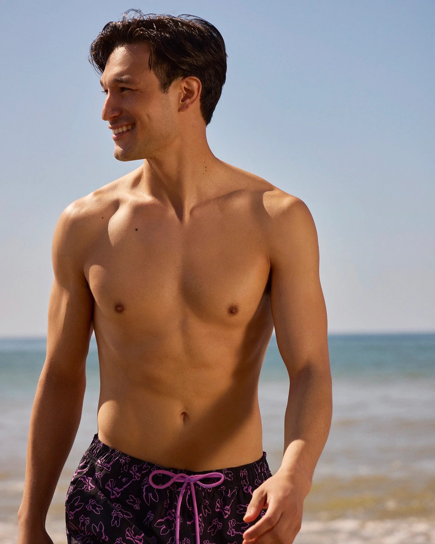 Male model wearing rendon print swim trunk in black on beach
