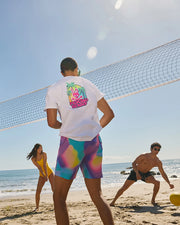 action shot of model wearing men's tyler print swim trunk playing at the beach