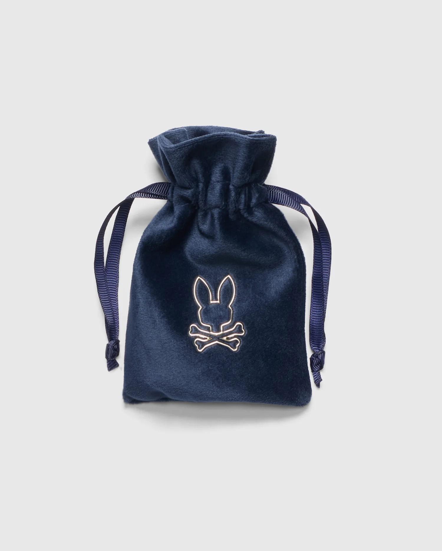 A blue velvet drawstring pouch with an embroidered Psycho Bunny logo, featuring a rabbit and crossbones for a sophisticated look. It’s tied with dark blue ribbons and set against a light gray background, complementing your MEN'S ROPE BRACELET - B6A368E200.